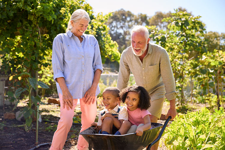 happy grandparents pushing their grandchildren in a wheel barrow retirement strategies